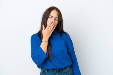 Genç Ukraynalı bir kadın beyaz arka planda izole edilmiş esniyor ve geniş bir ağzı eliyle kapatıyor.