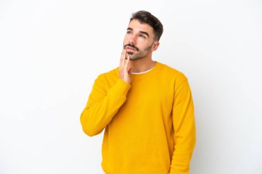 Beyaz arka planda izole edilmiş genç beyaz adam gülümserken yukarı bakıyor.