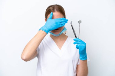 Beyaz arka planda izole edilmiş aletleri tutan beyaz dişçi kadın gözlerini elleriyle kapatıyor. Bir şey görmek istemiyorum.
