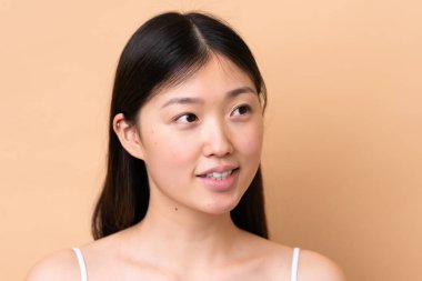 Genç Çinli kadın bej arka planda izole edilmiş. Portre