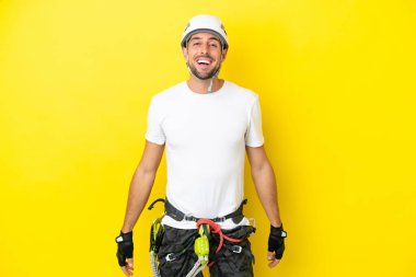 Genç kaya tırmanışçısı, sarı arka planda yalıtılmış, şaşırmış bir yüz ifadesi var.