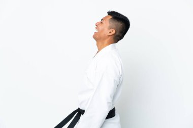 Genç Ekvadorlu adam beyaz arka planda karate yapıyor. Yan yana gülüyor.