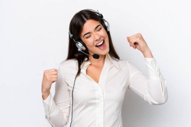 Beyaz arka planda izole edilmiş kulaklıkla çalışan beyaz pazarlamacı kadın zaferi kutluyor.