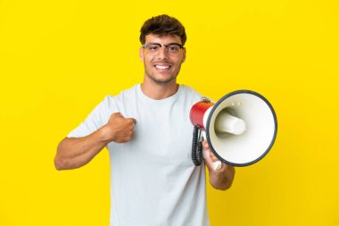 Sarı arka planda izole edilmiş, elinde megafonla ve şaşırmış bir yüz ifadesiyle genç, beyaz bir adam.