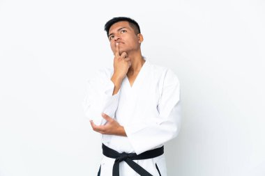 Genç Ekvadorlu adam beyaz arka planda karate yapıyor. Kafasını kaldırırken şüpheleri var.