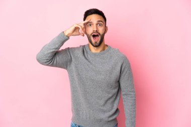 Pembe arka planda izole edilmiş genç beyaz adam bir şey fark etti ve çözüme niyetlendi.