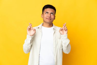 Genç Ekvadorlu adam sarı arka planda izole edilmiş, şans diliyor ve en iyisini diliyor.