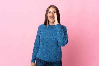 Pembe arka planda izole edilmiş genç Uruguaylı kadın ağzı açık bağırıyor.
