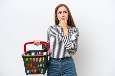 Genç Romen kadın elinde yiyecek dolu bir sepet tutuyor. Beyaz arka planda izole edilmiş, kuşkuları var.