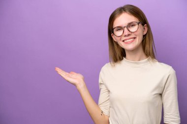 Mor arka planda izole edilmiş genç bir İngiliz kadın bir ilan vermek için avucunun içinde hayali bir mekan tutuyor.