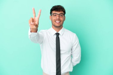 Mavi arka planda izole edilmiş beyaz bir adam gülümsüyor ve zafer işareti gösteriyor.