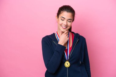 Pembe arka planda madalyaları olan Brezilyalı genç bayan yan tarafa bakıyor.
