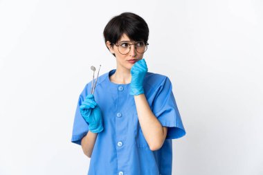 Beyaz arka planda izole edilmiş aletleri tutan dişçi kadının şüpheleri var