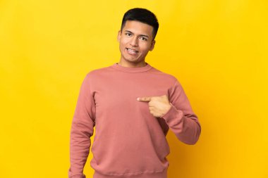 Genç Ekvadorlu adam, sarı arka planda yalıtılmış ve şaşırmış bir yüz ifadesi var.