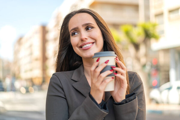 Young woman at outdoors holding a take away coffee and having doubts