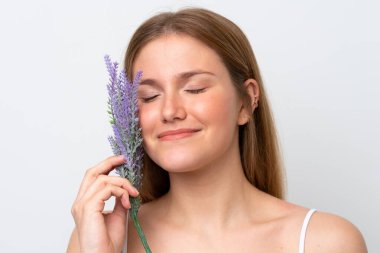 Beyaz arka planda, lavanta bitkisi tutan beyaz tenli genç bir kadın. Portreyi kapat