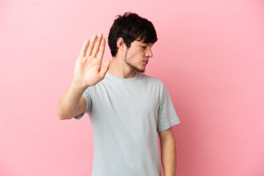 Pembe arka planda izole edilmiş genç bir Rus dur hareketi yapıyor ve hayal kırıklığına uğruyor.