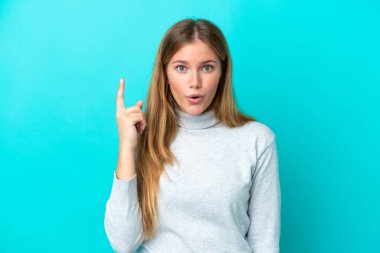 Mavi arka planda izole edilmiş genç sarışın kadın parmağını kaldırarak çözümü anlamaya çalışıyor.
