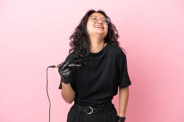 Dövme sanatçısı Asyalı kadın pembe arka planda yalnız gülüyor.