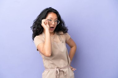 Restoran Asyalı garson mor arka planda gözlüklü ve şaşırmış.