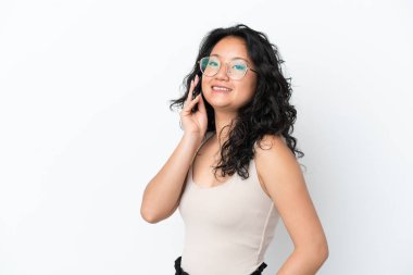 Beyaz arka planda izole edilmiş genç Asyalı bir kadın cep telefonuyla sohbet ediyor.