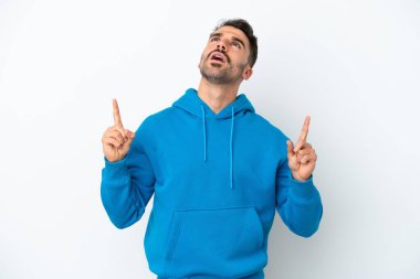 Beyaz arka planda izole edilmiş genç beyaz adam şaşırmış ve yukarı bakıyor.