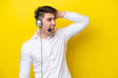 Tele pazarlamacı beyaz adam sarı arka planda izole edilmiş bir kulaklıkla çalışıyor. Bir şey fark etti ve çözümü arıyor.