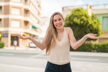 Açık havada gülümseyen genç sarışın kadın.