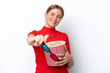 Beyaz arka planda 3 boyutlu gözlüklü ve elinde koca bir kova patlamış mısır tutan beyaz tenli bir kadın.