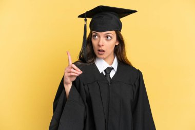 Genç üniversite mezunu. Sarı arka planda izole edilmiş.