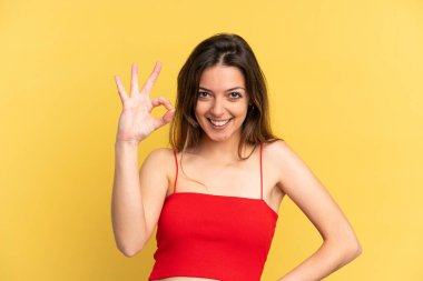 Sarı arka planda izole edilmiş beyaz kadın parmaklarıyla tamam işareti gösteriyor.