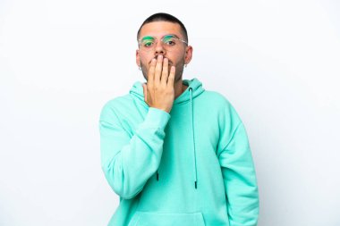 Beyaz arka planda izole edilmiş beyaz tenli genç bir adam ağızı eliyle kapatıyor.