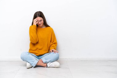 Young girl sitting on the floor isolated on white background laughing