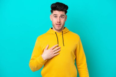 Mavi arka planda izole edilmiş genç beyaz adam kendini işaret ediyor.