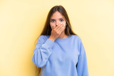 Sarı arka planda izole edilmiş, ağzı eliyle kapatan beyaz bir kadın.