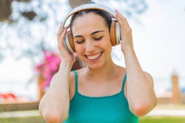 Açık havada müzik dinleyen genç ve güzel bir kadın.