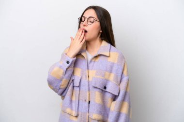 Beyaz arka planda izole edilmiş genç bir kız esniyor ve elleriyle ağzını kapatıyor.