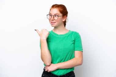 Beyaz arka planda izole edilmiş genç bir kadın bir ürünü sunmak için kenarı işaret ediyor.