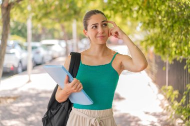 Açık havada genç ve güzel bir bayan öğrencinin şüpheleri var ve kafası karışık.
