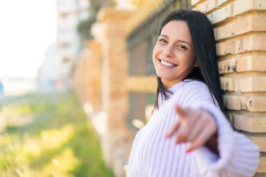 Açık alandaki genç kadın kendine güvenen bir ifadeyle seni işaret ediyor.