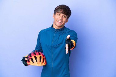 Mor arka planda izole edilmiş genç beyaz adam iyi bir anlaşma için el sıkışıyor.