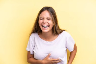 Sarı arka planda izole edilmiş genç beyaz kadın çok gülümsüyor.