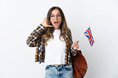 Beyaz arka planda izole edilmiş bir Birleşik Krallık bayrağı taşıyan genç Romen kadın telefon jesti yapıyor. Bana geri dönüş işareti ver.