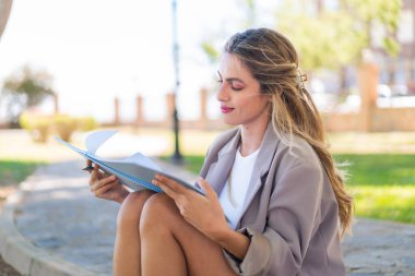 Genç, güzel sarışın Uruguaylı kadın elinde bir defter tutuyor.