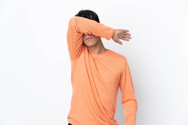 İzole edilmiş beyaz arka planı olan genç bir adam elleriyle gözlerini kapatıyor.