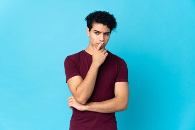 Genç Venezuelalı bir adam mavi arka planda izole edildi.