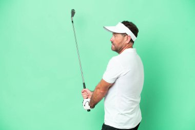Yeşil arka planda golf oynayan orta yaşlı beyaz bir adam.
