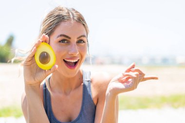 Avokado tutan genç sarışın kadın şaşırdı ve işaret etti.