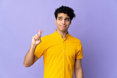 Genç Venezuelalı adam mor arka planda izole edilmiş, şans diliyor ve en iyisini diliyor.