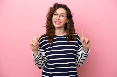 Pembe arka planda izole edilmiş beyaz bir kadın harika bir fikre işaret ediyor.